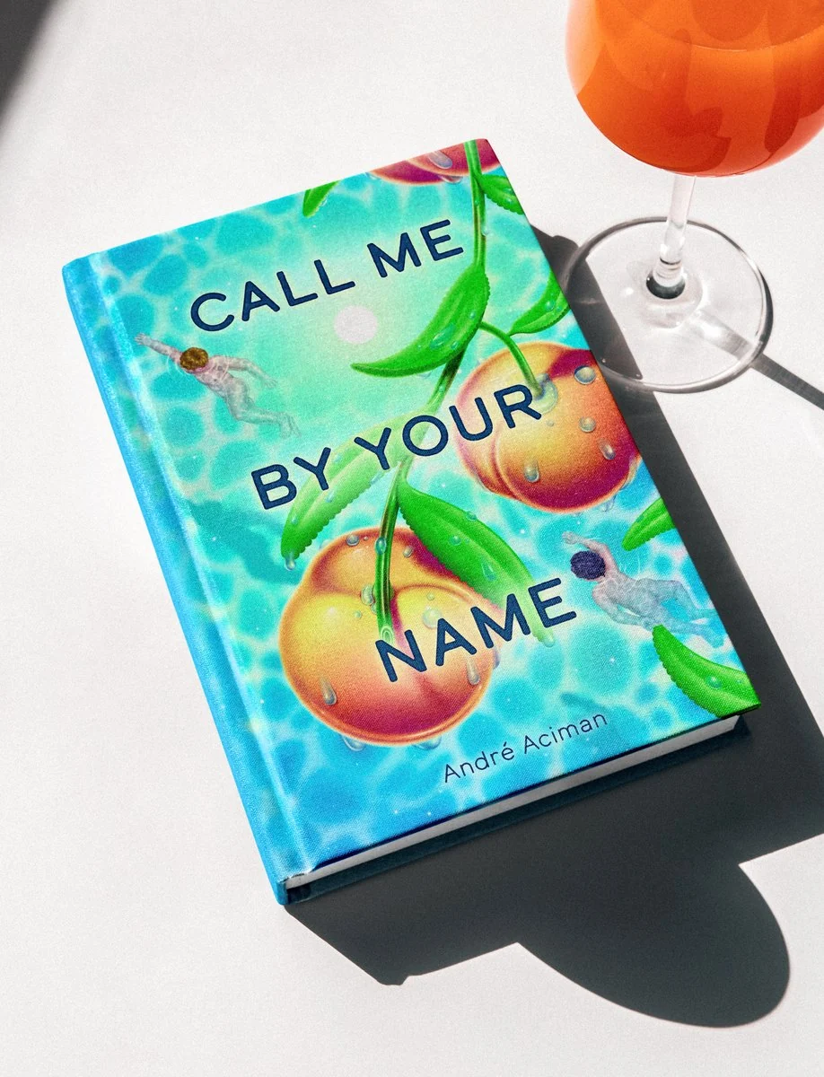 Call Me by Your Name book cover illustration: two swimmers among giant peaches, on a sunlit table beside a spritz