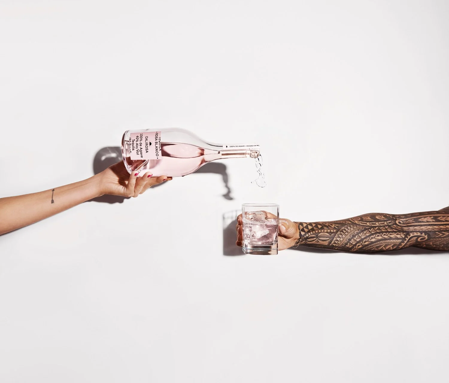 Two hands pouring Rosa Blanco tequila into a glass